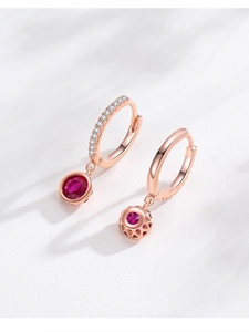 Détail macro de boucles d'oreilles créoles rose doré avec rubis rouges et dos alvéolé