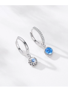 Detail of S925 silver hoop earrings with blue zircon drop and shimmering micro-pave stones