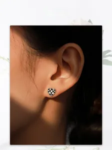 Détail macro d'une boucle d'oreille cœur à damier avec cristaux portée par le mannequin