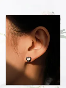 Gros plan de boucles d'oreilles cœur en argent S925 avec zircon noir et émail sur l'oreille