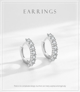 Détail macro de boucles d'oreilles huggie en argent 925 avec zircons sur texture blanche