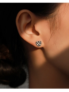 Gros plan sur boucle d'oreille cœur en argent S925 avec motif damier émail noir et blanc