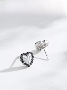 Vue macro de boucles d'oreilles cœur en argent S925 avec zircon noir et motif matelassé