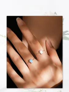 Macro detail of pear-cut opal stone chain rings on fingers with light and shadow effects