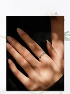 Artistic detail of geometric S925 silver criss-cross diamond ring on model finger