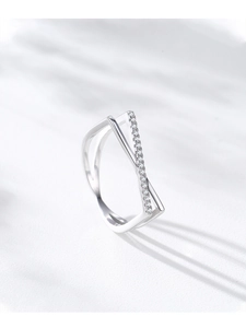 Macro shot of silver crisscross ring featuring micro-pave diamonds on a textured background