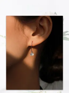 Close-up of a minimalist sterling silver hook earring with a faceted zircon stone