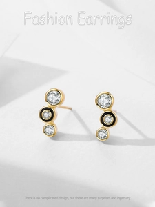 Dettaglio macro di orecchini dorati con smalto nero e micro-pavé di diamanti brillanti