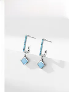 Detailed view of silver drop earrings featuring turquoise beads and rhombus pendants