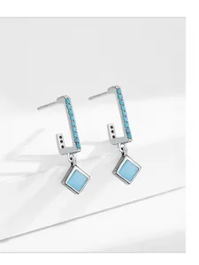 Macro detail of geometric S925 silver earrings with square blue turquoise stone drops