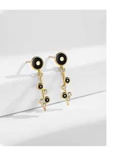 Macro shot of gold-plated drop earrings featuring black enamel accents and zircon stones