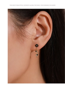 Detail of gold bubble drop earrings with black enamel and zircons worn by model