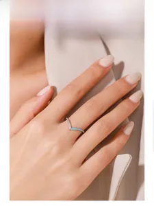 Gros plan d'une bague en V avec émail bleu et cristaux étincelants portée au doigt