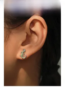 Detail of S925 silver lizard stud earring with green enamel and purple zircon on ear