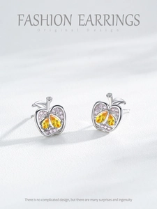 Gros plan des boucles d'oreilles pomme en argent avec pierres jaunes et pavé rose