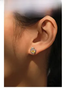 Gros plan d'une boucle d'oreille pomme en argent S925 avec pierres jaunes sur l'oreille