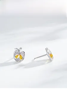 Gros plan de boucles d'oreilles pomme en argent avec pierres jaunes et cristaux roses