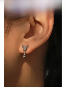 Vue macro d'une boucle d'oreille scorpion en argent avec pierres noires et étoile