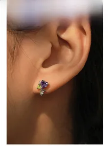 Close-up of S925 silver heart stud earring with purple zircon worn by a model