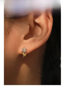 Close-up of S925 silver flower stud earring with pink and yellow zircon inlays on ear