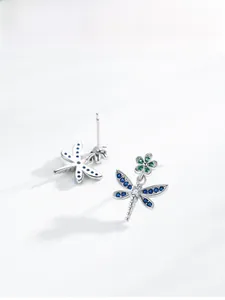 Detail of silver dragonfly stud earrings with blue wings and green stone floral accent