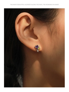 Macro detail of S925 silver heart earring with purple and green stones on model
