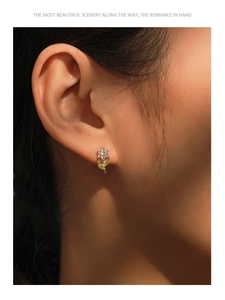 Close-up of colorful flower stud earrings with pink and yellow zircons on silver base