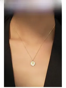 Gros plan d'un collier en argent S925 plaqué or avec pendentif rose en émail blanc