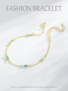 Detail of gold bracelet with blue and mint green enamel charms and lobster clasp