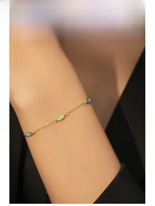 Model wearing a minimalist gold silver bracelet with green enamel olive-shaped pendants