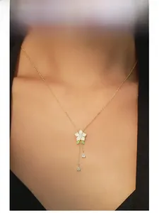 Collier orchidée dorée avec pétales en émail blanc et pendentifs zircon poire sur le modèle