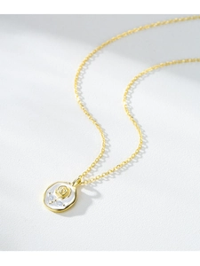 Vue détaillée d'une rose dorée en relief sur émail blanc avec pierres en zircon