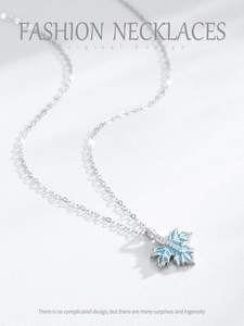 Macro view of blue enamel maple leaf pendant with white zirconia pavé on silver chain
