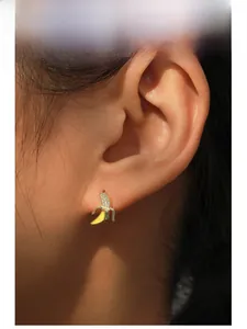 Close-up of model wearing yellow enamel banana stud earrings with micro-set diamonds
