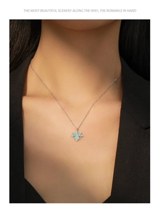 Close-up of S925 silver necklace with blue enamel maple leaf pendant on a black blazer