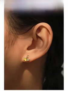 Macro shot of 14K gold-plated ginkgo leaf stud earrings with yellow enamel veins