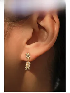Detail of S925 silver daisy earring with enamel petals and leaf-shaped zircon drop
