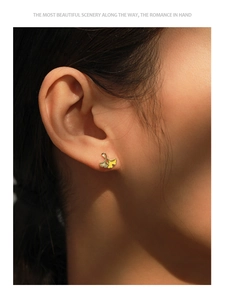 Detail view of 14K gold plated S925 silver ginkgo leaf stud earring on model ear lobe
