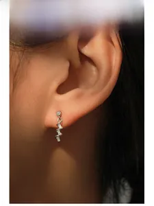 Close-up of elegant silver wave spiral earrings with micro-inlaid zircon on ear lobe