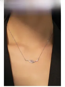 Detailed view of silver wheat pendant with pink and white stones on a model's neck