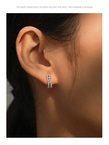 Macro shot of S925 silver wave earrings with sparkling cubic zirconia on model ear