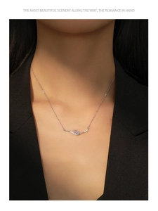 Detail of silver wheat ear necklace with pink and clear stones worn on a black blazer