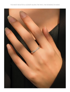 Macro shot of silver crisscross ring with pavé zircons worn on model finger
