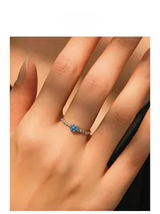 Detailed shot of a silver heart ring with blue stone and twisted rope band texture