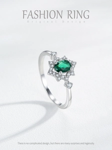 Macro shot of oval emerald gemstone ring with sparkling diamond halo in silver setting