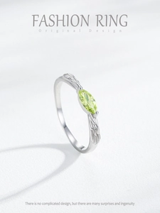 Detailed macro view of marquise-cut green gemstone with feather carvings on silver ring