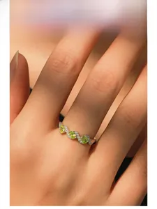 Detail of S925 silver ring featuring three green zircons and wavy diamond lines on finger