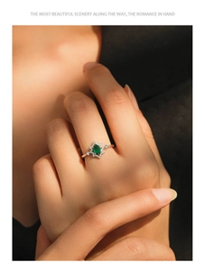 Close-up of vintage S925 silver ring with oval emerald and diamonds on finger