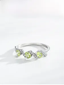 Macro detail of S925 sterling silver ring with green zircons and wave band texture