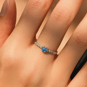 Romantic heart-shaped blue gemstone ring with silver twisted band on finger